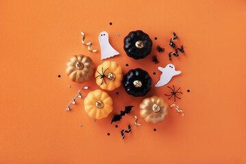 Halloween holiday background with party decorations of pumpkins, bats, ghosts on orange top view. Happy halloween greeting card in flat lay style.