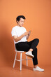© 1112000 - man sitting on chair  isolated on orange background