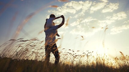 father and son in the park. father's day silhouette happy family child dream concept. father carries his son on his back. dad playing with his son in nature in the park silhouette at sunset lifestyle