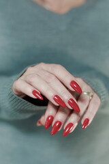 Wall Mural - Female hand with long nails and a bright red manicure holds a bottle of nail polish