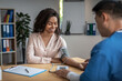 © Prostock-studio - Adult asian man doctor measures pressure of smiling young black female patient in clinic office interior