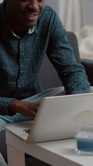 Poster - Vertical video: Authentic smiling black african american guy working from home, remote worker computer laptop user. Black freelancer using internet web online communication in modern flat