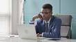 © stockbakers - Young African Businessman Thinking while Working on Laptop in Office