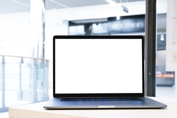 Wall Mural - Laptop with white screen in business office or shopping mall. Empty copy space, blank screen mockup. Soft focus laptop with interor background. Travel, study and office work concept