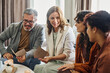 © pressmaster - Happy mature parents with wedding invitations sitting on couch in front of lesbian couple and discussing forthcoming event with them