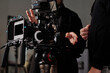 © pressmaster - Modern steadicam against videographer and his assistant in black casualwear discussing working moments in studio