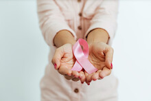 Close-up Of Woman's Hands Holding Pink Ribbon. Breast Cancer Awareness Concept