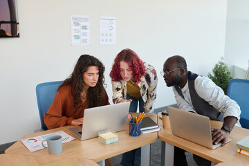 Poster - Group of young multicultural coworkers in casualwear consulting about new business project while preparing its presentation