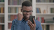 © stockbakers - Young African Man Celebrating Win on Smartphone