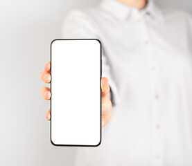 Poster - Woman holding phone mockup in vertical position. Female using smartphone for showing photo or information. Telephone template with blank display