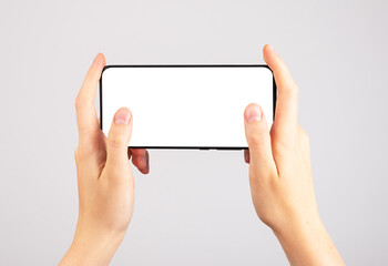 Poster - Hands holding phone mockup in horizontal position. Woman using smartphone for playing games. Mobile gaming. template with blank display