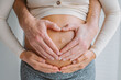 © Maridav - Loving parents heart shape hands on pregnant woman belly. Expecting couple in love pregnancy closeup photo of belly.