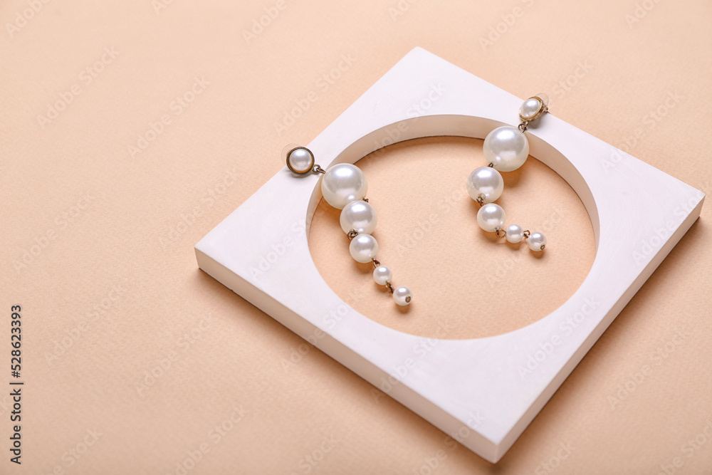 Stylish pearl earrings on beige background