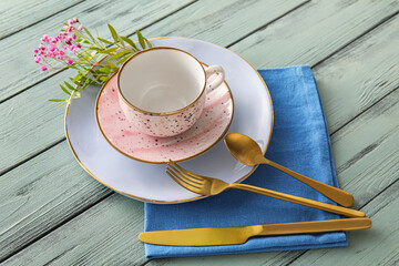 Stylish table setting with porcelain cup and cutlery on color wooden background