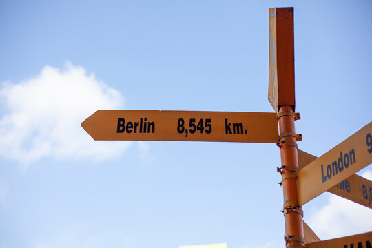 Signs giving directions to different cities against a clear sky background.