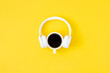 A cup of black coffee and white headphones on yellow background. Minimal style, Flat lay, Top view. Education concept