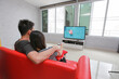 © jayzynism - Couple love watch summer trip together in living room at home. Attractive romantic man and woman sitting on red sofa.