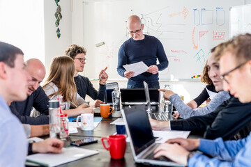 Wall Mural - Startup business and entrepreneurship problem solving. Young AI programmers and IT software developers team brainstorming and programming on desktop computer in startup company share office space.