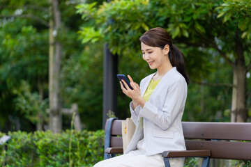 Poster - 公園のベンチに座ってスマホを見る女性