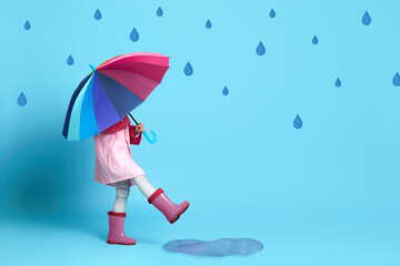 Wall Mural - child girl with multicolored umbrella in pink rain coat