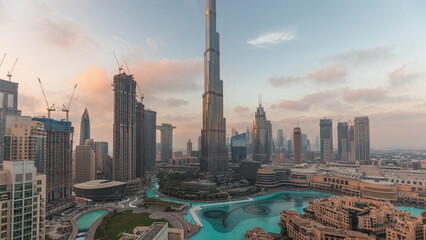 Skyscrapers rising above Dubai downtown day to night timelapse surrounded by modern buildings aerial top view