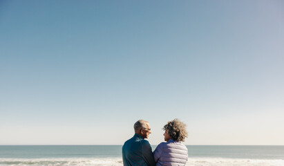 Wall Mural - Happy elderly couple smiling at each other at the beach