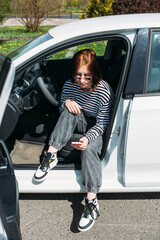 Portrait of a young brunette woman driving in a car using a smartphone