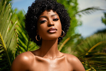 Wall Mural - Fashion beauty portrait of African american model . Beautiful woman posing  against green exotixc palms trees background.