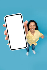 Poster - Above view of young woman pointing at mobile phone with blank screen, advertising website, offering space for ad mockup