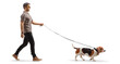 Full length profile shot of a cool young man walking a basset hound dog on a lead