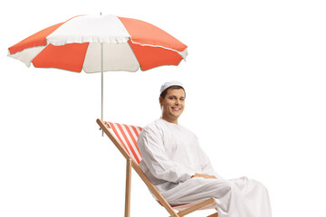 Wall Mural - Man in ethnic clothes sitting in a beach chair under umbrella