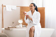 © Prostock-studio - Woman Holding Opened Moisturizer Jar Caring For Skin In Bathroom