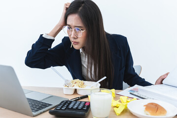 Asian b busy with work, where she eats while working because she hastened to complete the work according to the goal, to business and work so busy that you don't have time to eat concept