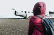 Woman on winter clothes in front of the wreck of th crashed airplane in Iceland, on the beach of Sólheimasandur. Travel to Iceland, road trip concept. Copy space image, visit Iceland.