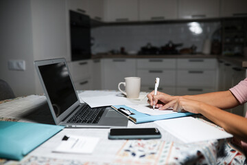 works at the computer on the table near the kitchen