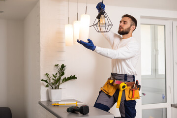 Electrician installs lamp lighting and spot loft style on ceiling.