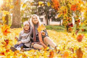 Wall Mural - happy family: mother and child little daughter play cuddling on autumn walk in nature outdoors