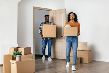 Wall Mural - Cheerful Black Couple Entering New House Carrying Moving Boxes Indoor