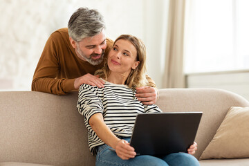 Wall Mural - Happy Middle Aged Couple Using Laptop Computer At Home