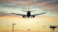The Silhouette Of A Passenger Plane Coming In For Landing Against The Backdrop Of The Sunset Sky.