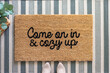 Top view of a stylish welcome mat that says Come on in and cozy up