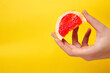 © tanitost - Defocus female hand holding piece of a red grapefruit. Healthy food concept.  Fresh orange juice. Vegan, vegetarian concept. Banner with copy space. Citrus fruit. Out of focus