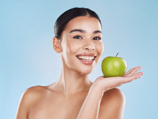 Wellness, health and beauty with woman and an apple for nutrition, detox and green diet against a blue background. Nutritionist, smile and fruit with happy female eating healthy for natural lifestyle