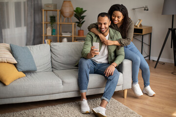 Wall Mural - African American Husband And Wife Using Phone Sitting At Home