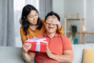 Loving asian woman making surprise for her boyfriend, giving present