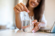 © Graphicroyalty - Closeup of a young woman dropping an effervescent antacid in a glass of water. young woman hardly put a soluble pill with a medicine for pain or a hangover in a glass of water