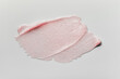 © colnihko - Smears of transparent pink lip gloss or moisturizer with glitter on grey background. Body highlighter swatch
