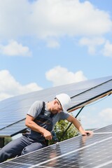 Male engineer in protective helmet installing solar photovoltaic panel system. Alternative energy ecological concept.