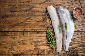 Wall Mural - Raw fish fillets on grill with rosemary and herbs. Wooden background. Top view. Copy space