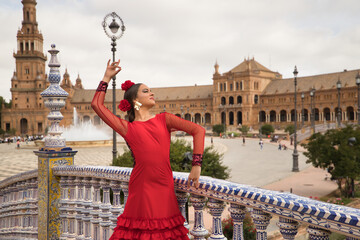 Sticker - Young teenage woman in red dance suit with red carnations in her hair doing flamenco dance poses. Flamenco concept, dance, art, typical Spanish dance.